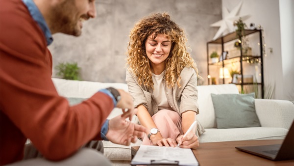 dos personas en un sofá firmando un documento